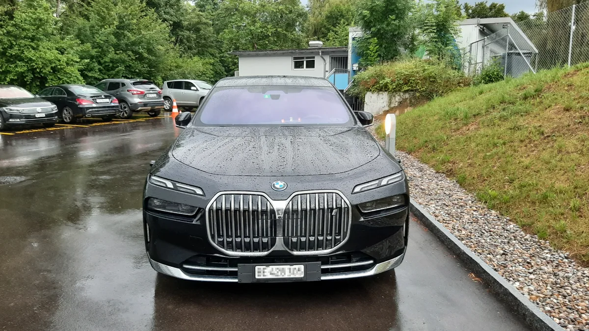 Ein schwarzer Luxus-BMW mit getönten Scheiben steht auf einer asphaltierten Fläche.
